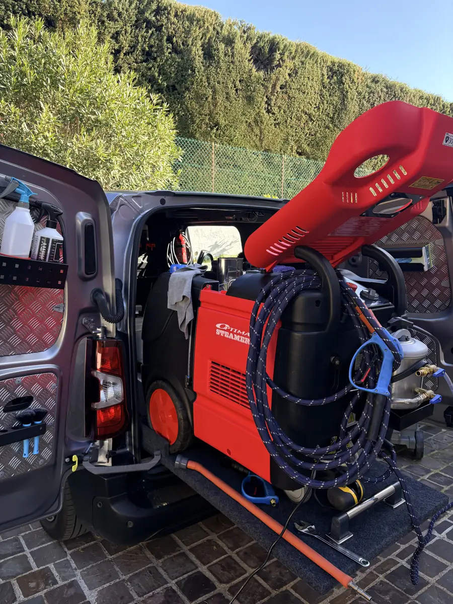 Intérieur du camion atelier Unick Wash : machine vapeur rouge, flexible tressé et produits rangés sur la porte