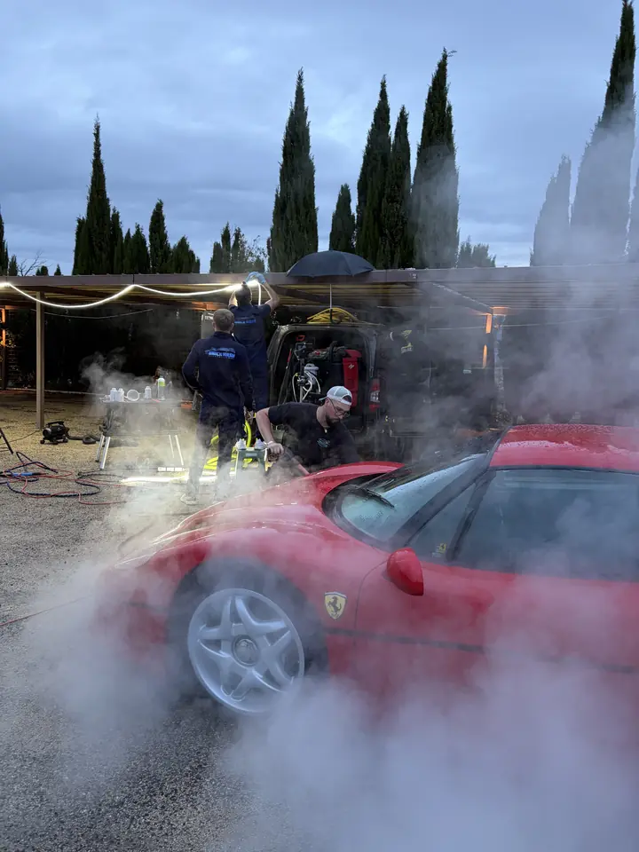 Ferrari F50 rouge enveloppée de vapeur pendant le nettoyage, équipe Unick Wash au travail