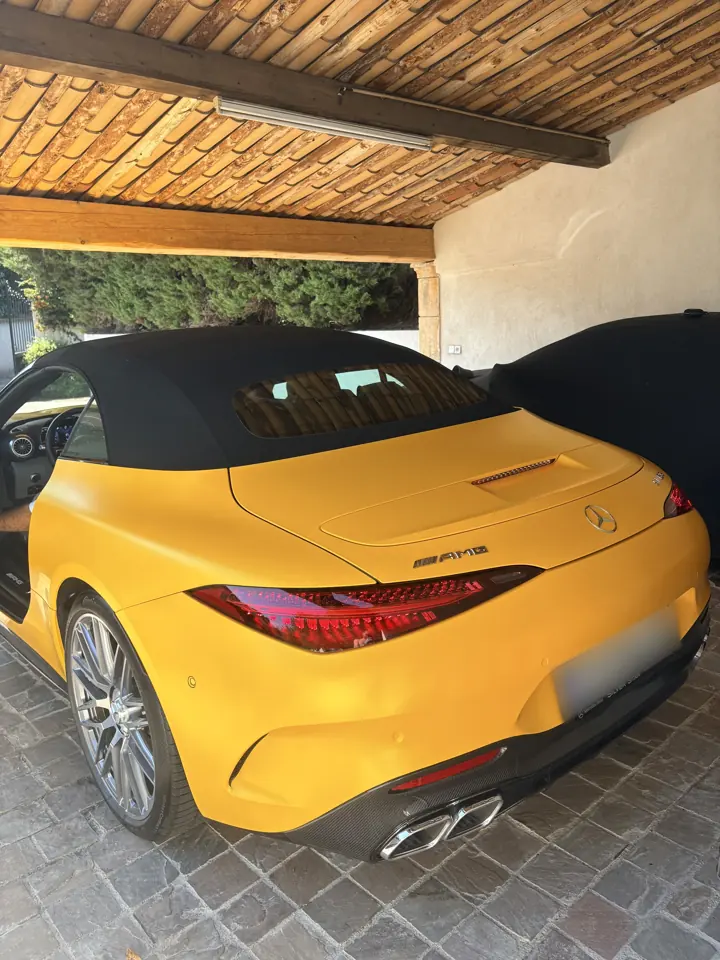 Mercedes-AMG SL 63 jaune mat, capote noire, vue arrière sous un carport